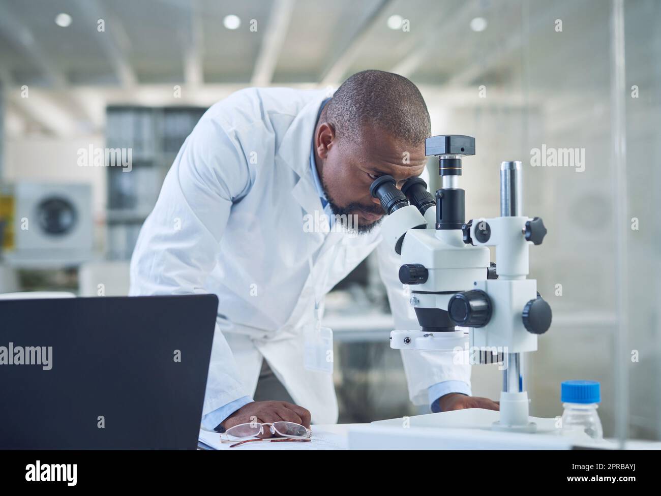 Il maestro stesso della ricerca medica. Uno scienziato che usa un microscopio mentre conduce la ricerca in un laboratorio. Foto Stock