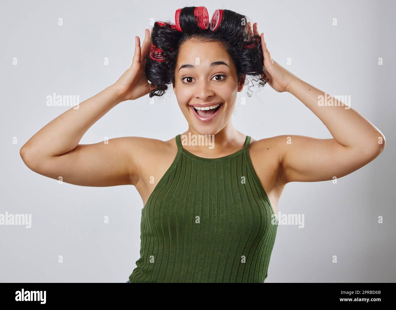 Non vedo l'ora di vedere il whatll assomiglia. Una giovane donna che posa con i rulli dei capelli su uno sfondo grigio. Foto Stock
