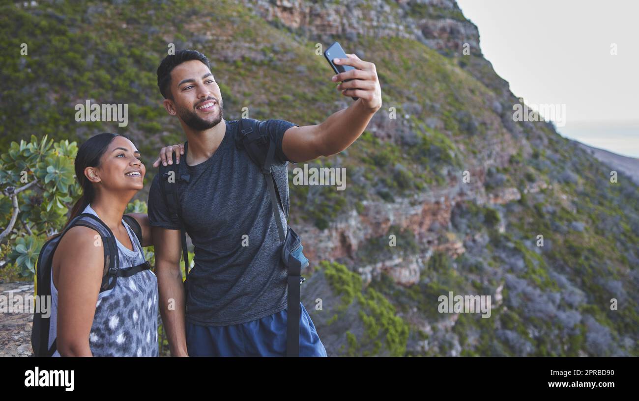 Le escursioni con voi sono sempre le migliori. Una giovane coppia scatta foto mentre si fa un'escursione in una catena montuosa all'aperto. Foto Stock