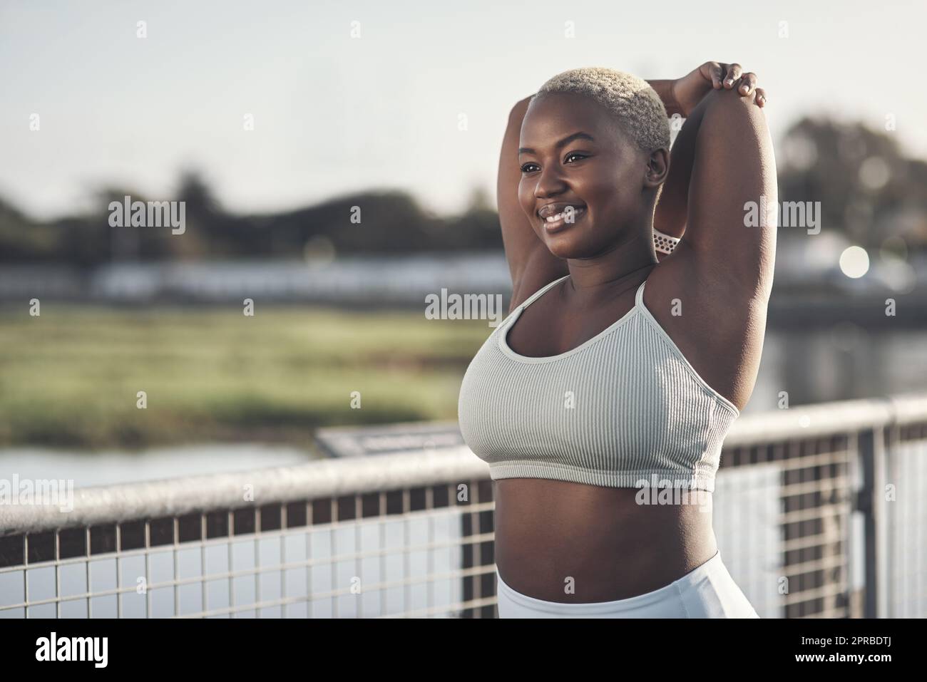 Mi stretch perché mi fa sentire bene, una giovane donna attraente che si estende all'esterno. Foto Stock