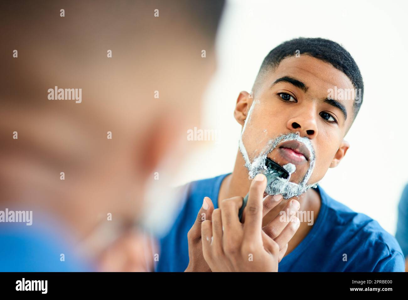 È il momento di essere pulito rasare ancora un po 'di tempo. Un giovane concentrato che controlla il suo riflesso come lui rasa il viso. Foto Stock