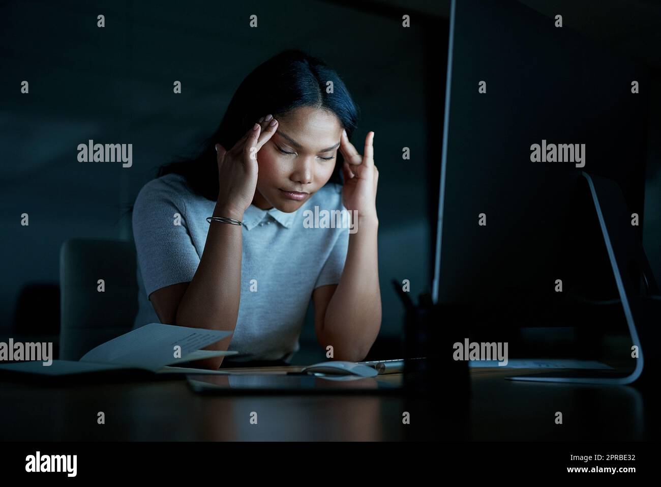 Ciò che oggi sembra impossibile potrebbe ancora ripagare domani: Una giovane donna d'affari che guarda stressata mentre usa un computer durante una notte tarda al lavoro. Foto Stock