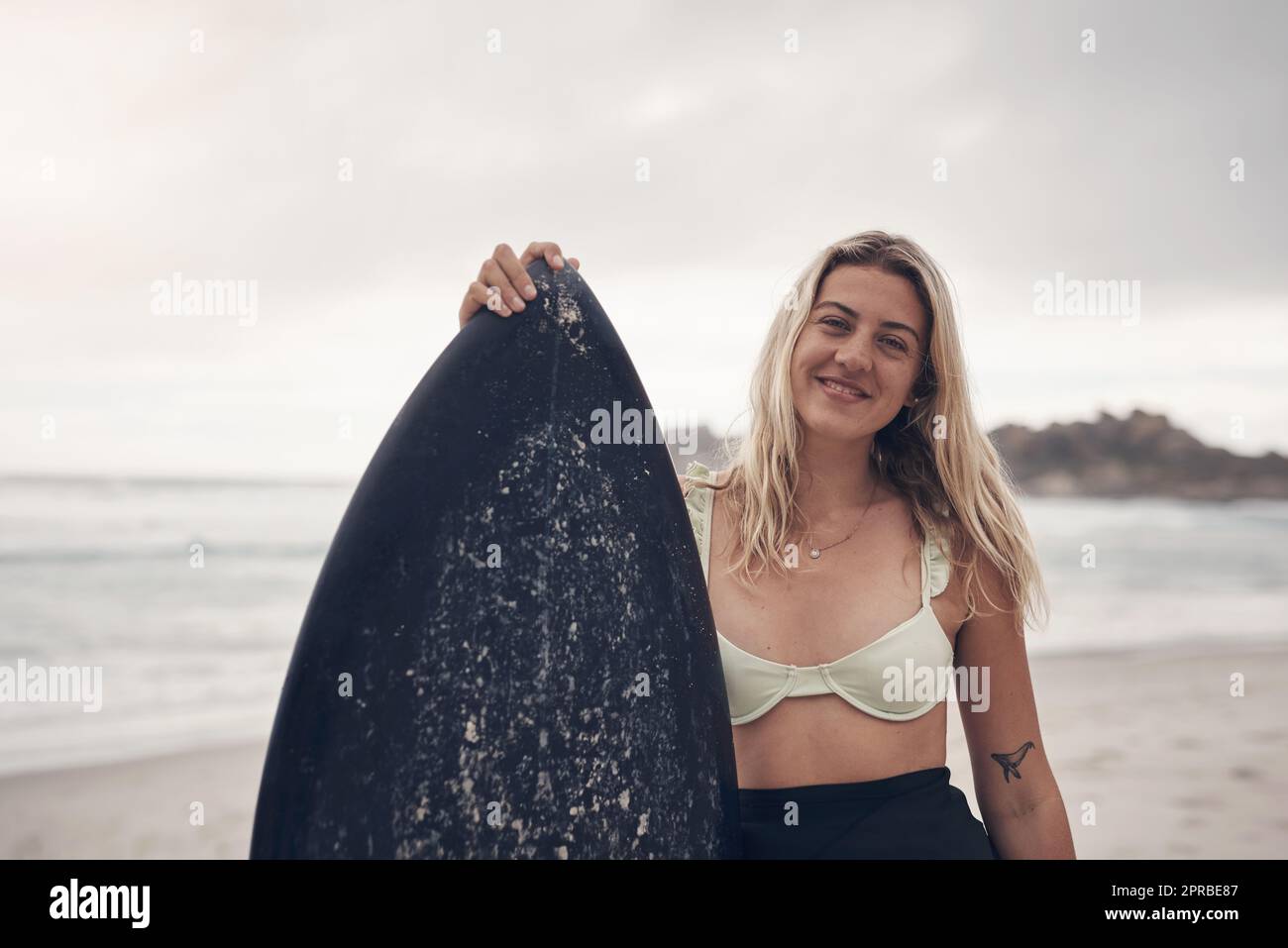 Una tavola da surf è tutto ciò di cui avete bisogno: Una giovane donna in piedi sulla spiaggia con la sua tavola da surf. Foto Stock