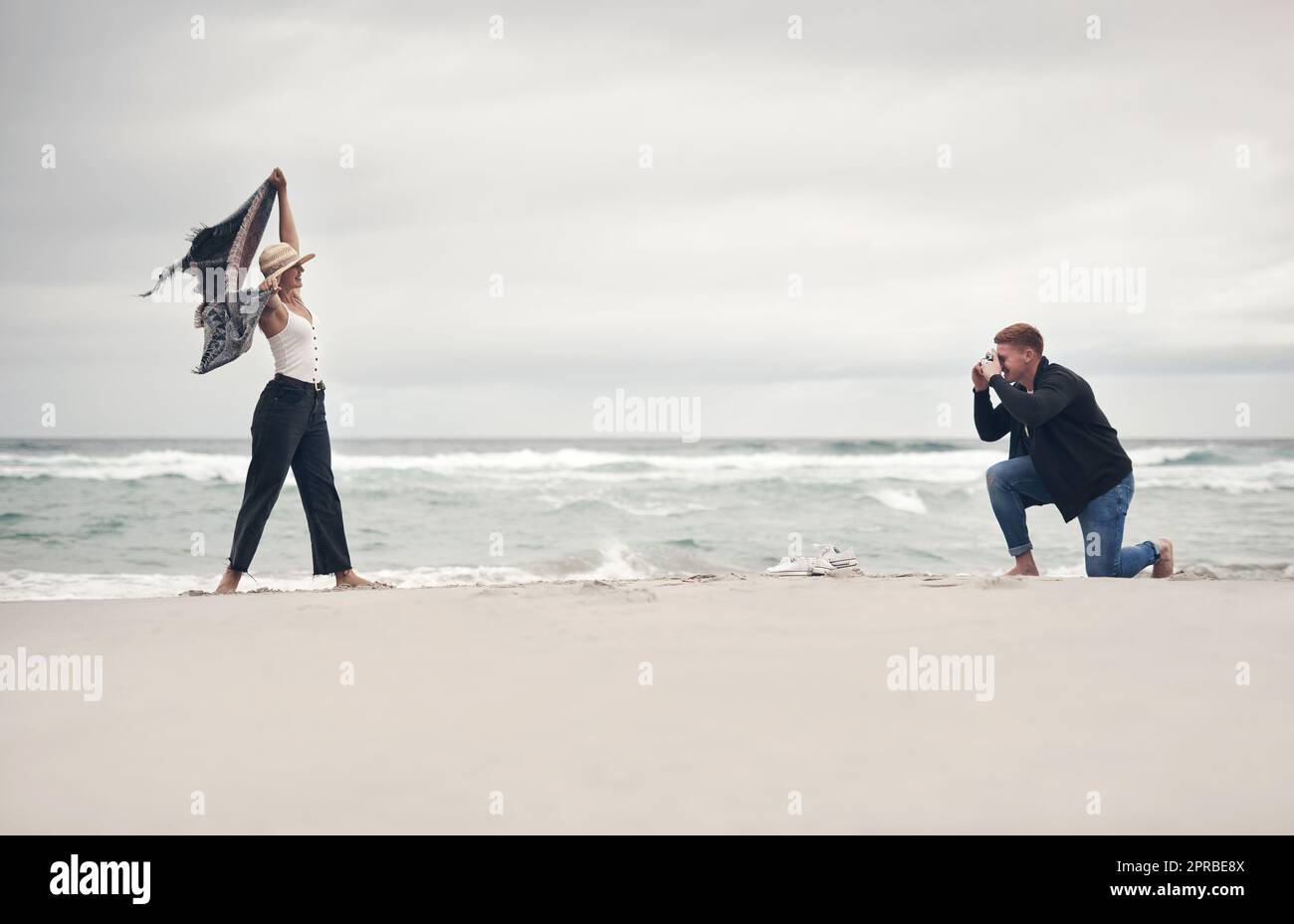 Mettiti in posa, babe. Un uomo che scatta foto della sua ragazza mentre trascorre del tempo in spiaggia. Foto Stock