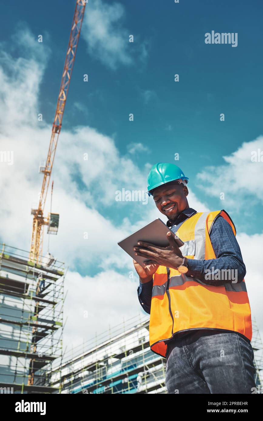 La soluzione di gestione dei progetti più intelligente. Un giovane che utilizza un tablet digitale mentre lavora in cantiere. Foto Stock