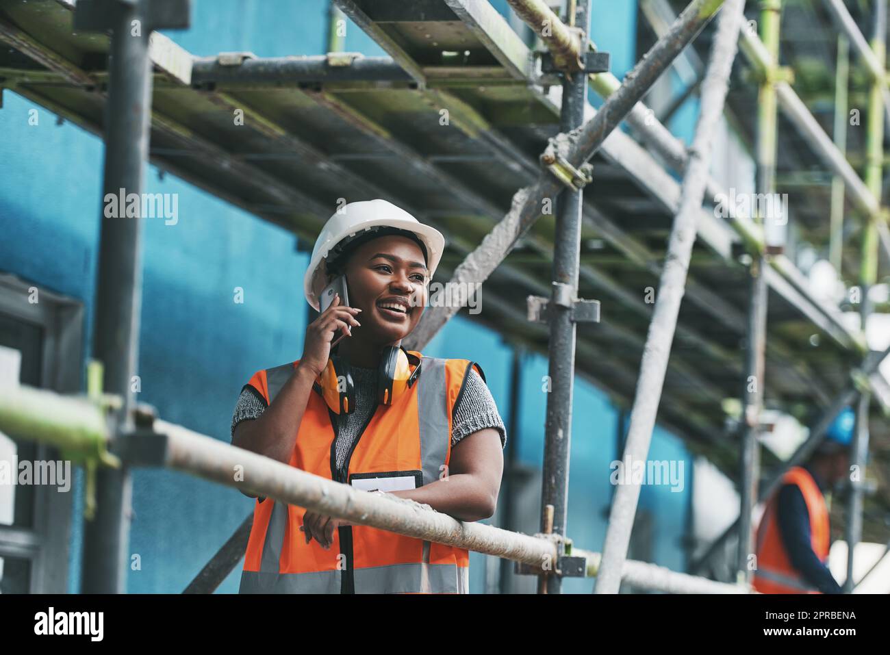 Voi lo volete, lo costruiamo, una giovane donna che parla su un cellulare mentre lavora in un cantiere. Foto Stock