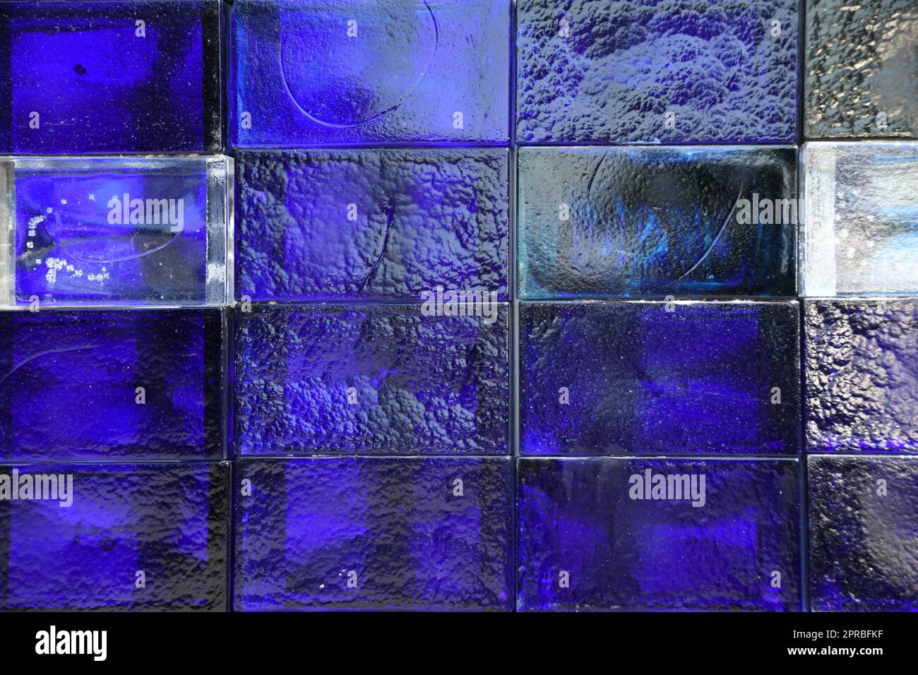 I mattoni di vetro sono spesso utilizzati come divisori per ambienti e sostituzioni di finestre. Il colore del blocco di vetro è da blu a blu scuro. Sono felici che queste pietre siano illuminate. Foto Stock
