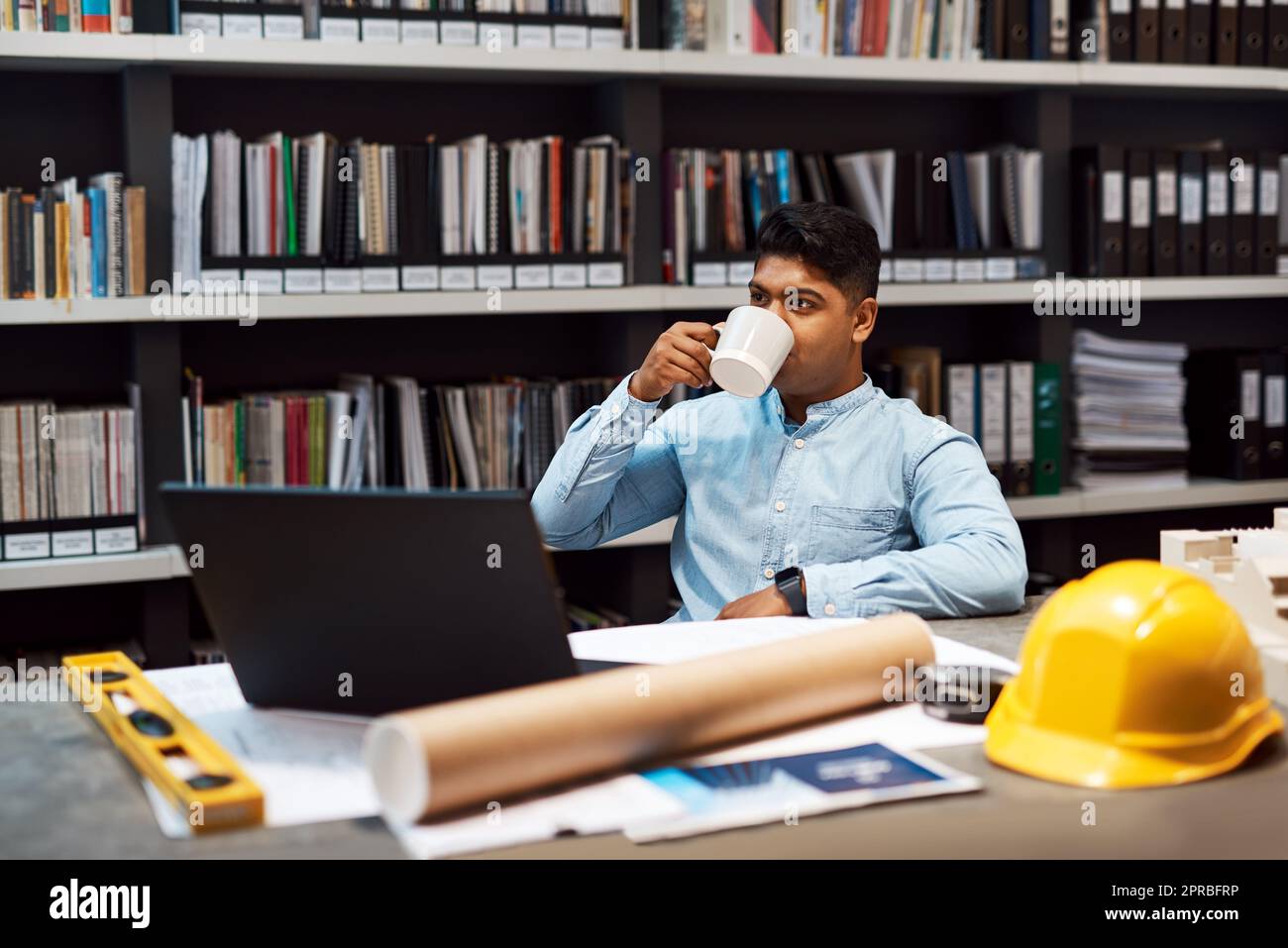 È il momento di costruire un sogno ma il primo caffè. Un giovane architetto che ha una pausa caffè mentre lavora in un ufficio moderno. Foto Stock