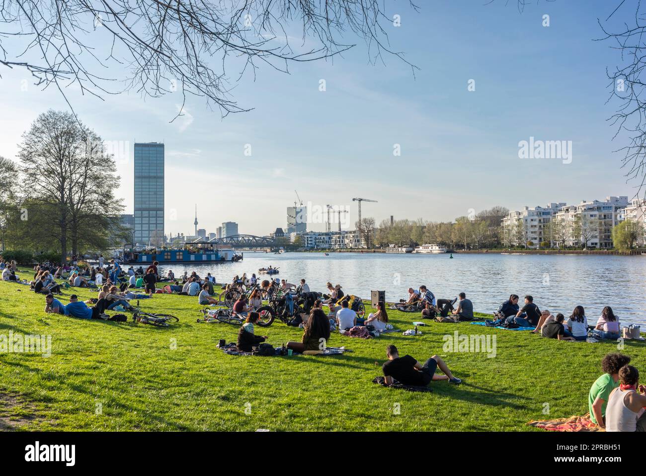 Persone che prendono il sole sulle rive del fiume Sprea durante la primavera al Treptower Park durante una calda giornata primaverile a Berlino Treptow, Germania, Europa Foto Stock