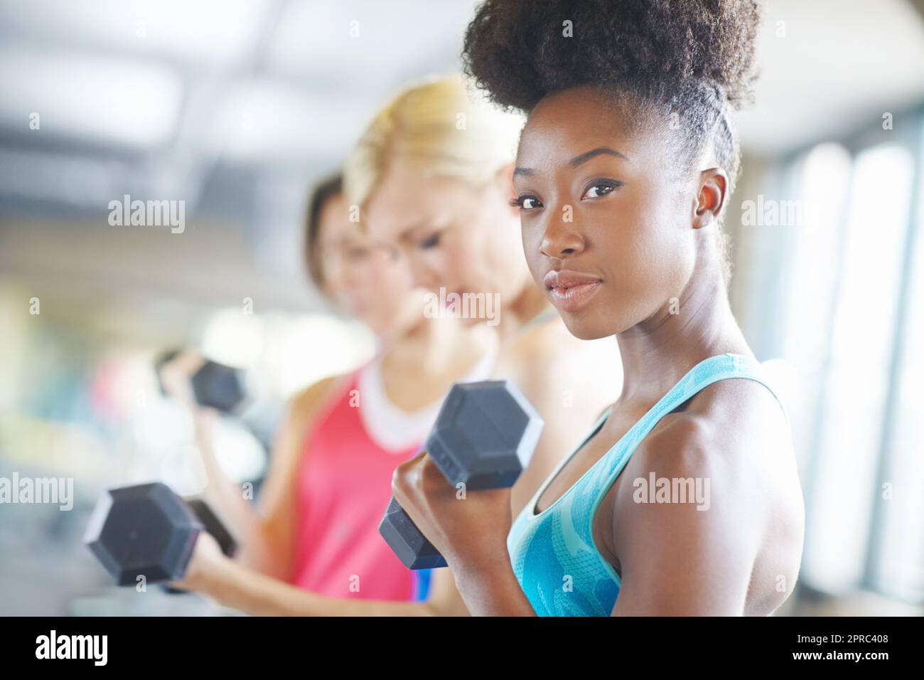 Fitness di squadra. Un colpo di tre donne allineate in palestra mentre si sollevano i pesi. Foto Stock Fitness di squadra. Un colpo di tre donne allineate in palestra mentre si sollevano i pesi. Foto Stock