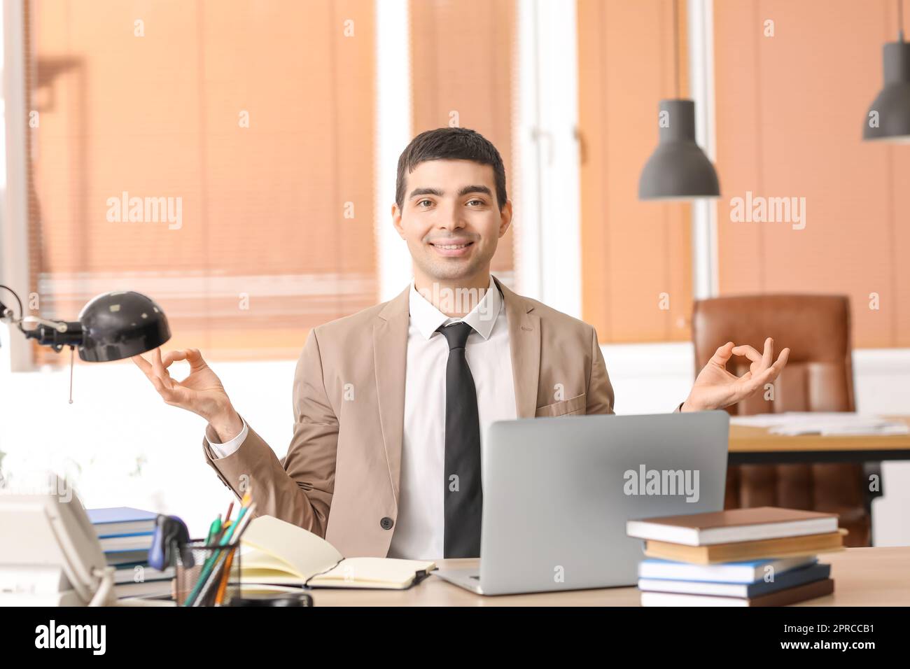 Giovane uomo d'affari che medita in ufficio. Concetto di equilibrio Foto Stock