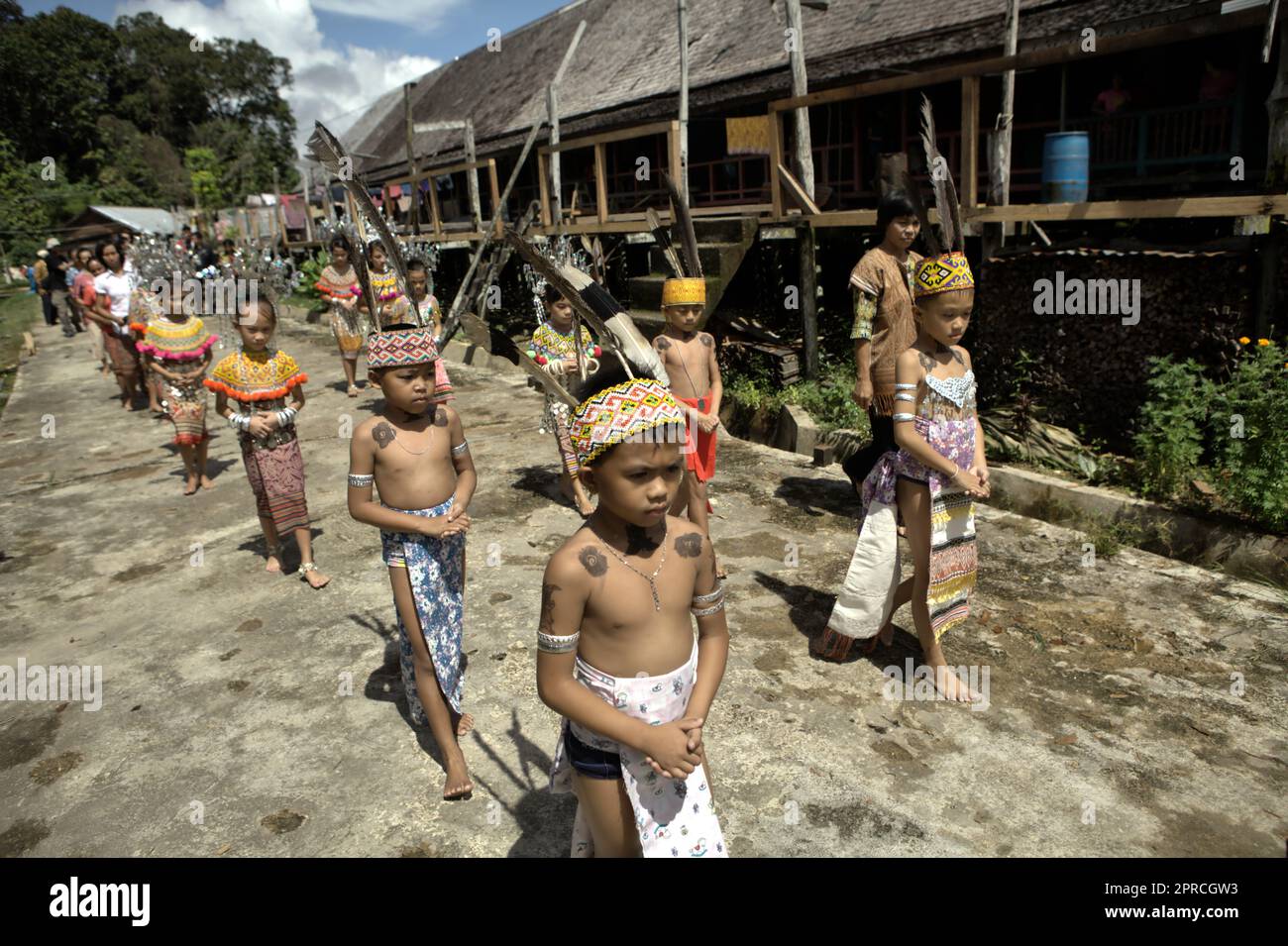 Bambini in abbigliamento tradizionale in fila per una cerimonia di benvenuto durante un evento ecoturismo al di fuori della comunità tradizionale IBAN Dayak a Sungai Utik, Kapuas Hulu, Kalimantan occidentale, Indonesia. Basata su una fede e uno sforzo continui per proteggere il loro ecosistema circostante (foresta, acqua, terra) e le tradizioni culturali, questa comunità è stata considerata una delle comunità indigene di maggior successo nel paese nella gestione di attività economiche sostenibili, come il turismo eco-culturale. Foto Stock