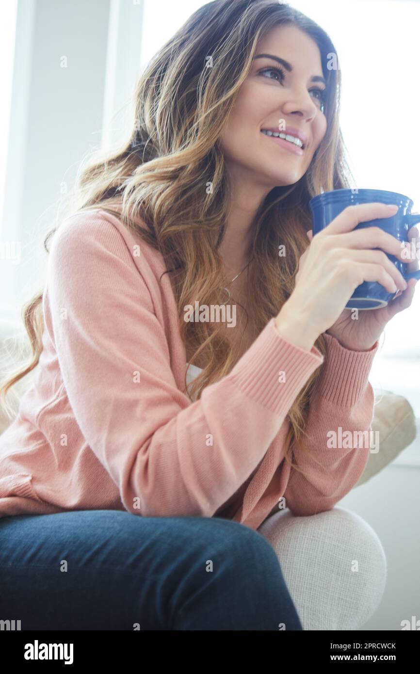 Prendendosi il giorno per rallentare e vento giù. una bella giovane donna che ha un caffè mentre si rilassa a casa. Foto Stock
