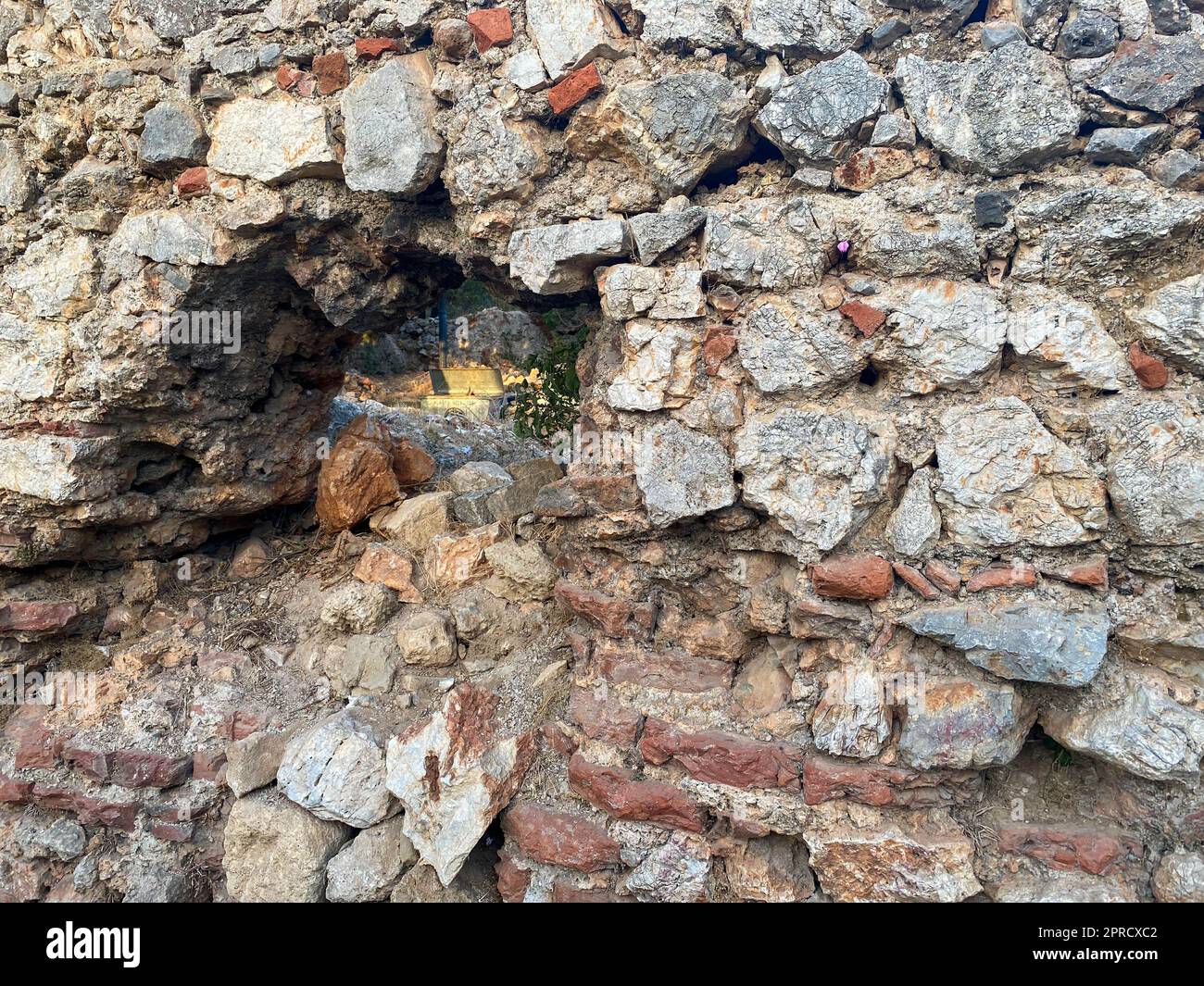 Sfondo, texture, muro di pietra di pietre rotonde ciottoli mattoni superficie naturale naturale affilato convesso ruvido pietra di ciottoli con crepe. Foto Stock