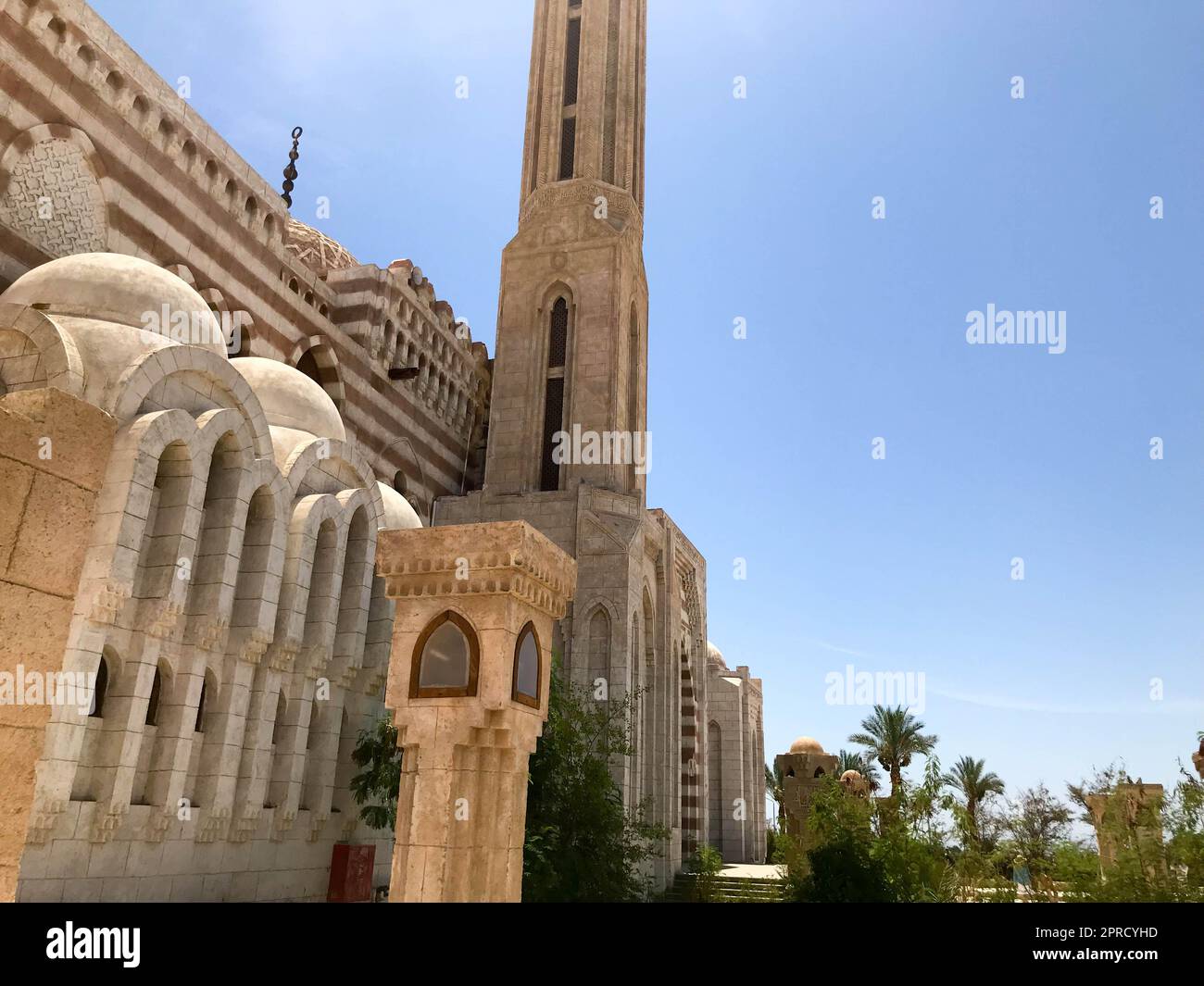 Una grande moschea islamica araba in pietra beige, un tempio per le preghiere di un dio con un'alta torre in un caldo paese tropicale. Foto Stock