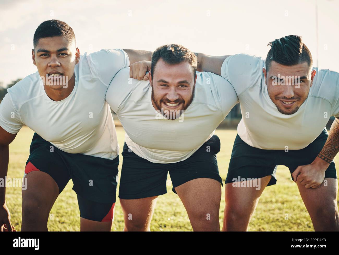 Sapete per cosa ci siamo. Ritratto ritagliato di un gruppo di tre giovani giocatori di rugby che si allineano per una mischia sul campo durante il giorno. Foto Stock