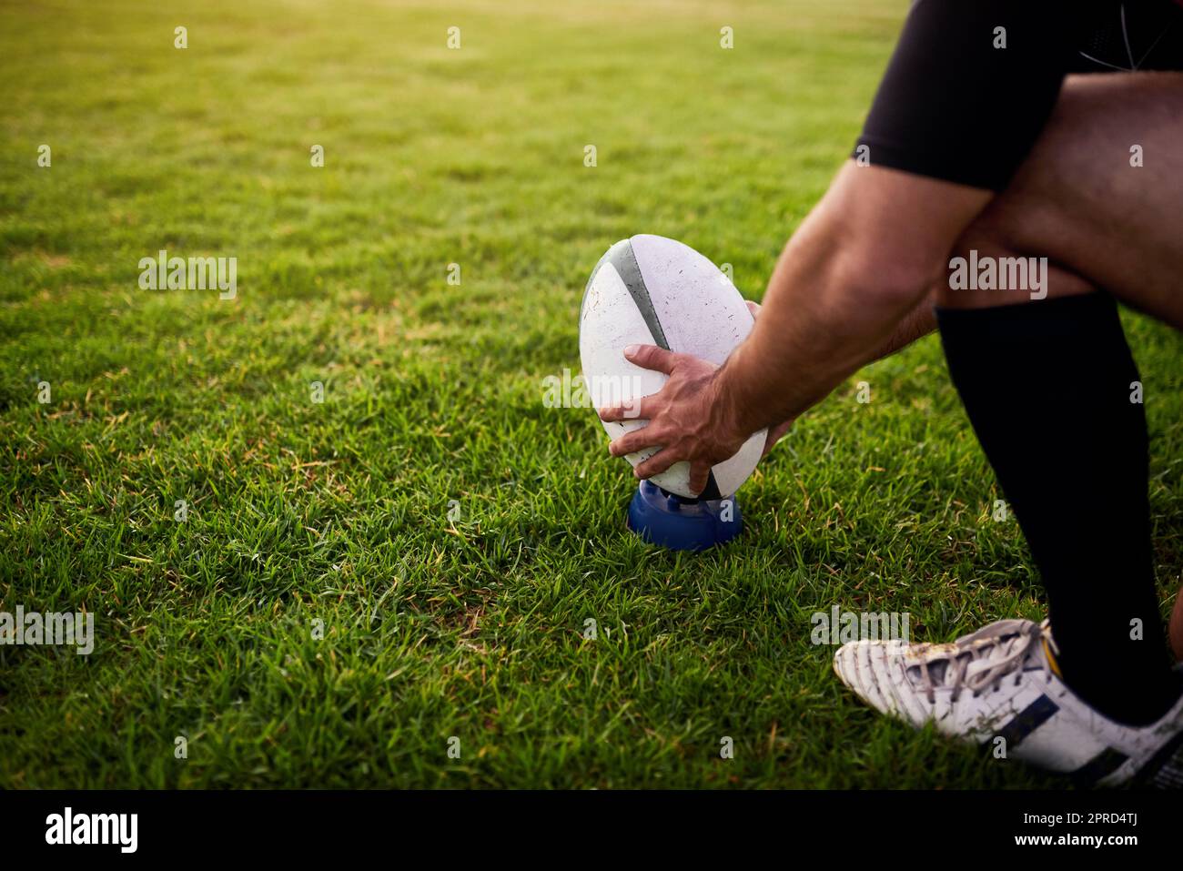 Lavorando sulla mia abilità, uno sportivo irriconoscibile che si accovacciava da solo durante la pratica del rugby in un club sportivo. Foto Stock