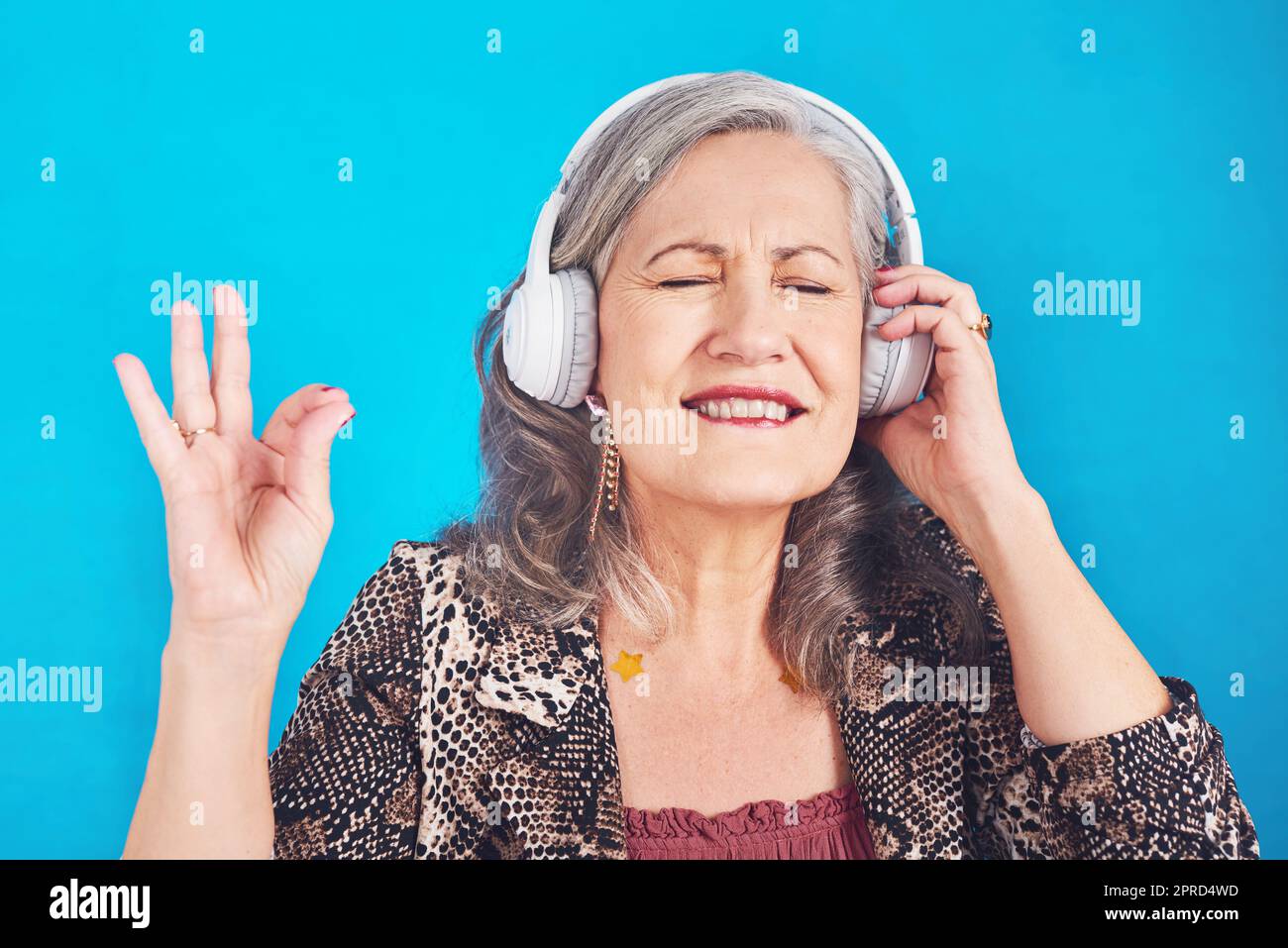 Questa canzone mi riporta ai bei vecchi tempi. Una donna funky e allegra che ascolta la musica sulle cuffie su sfondo blu. Foto Stock