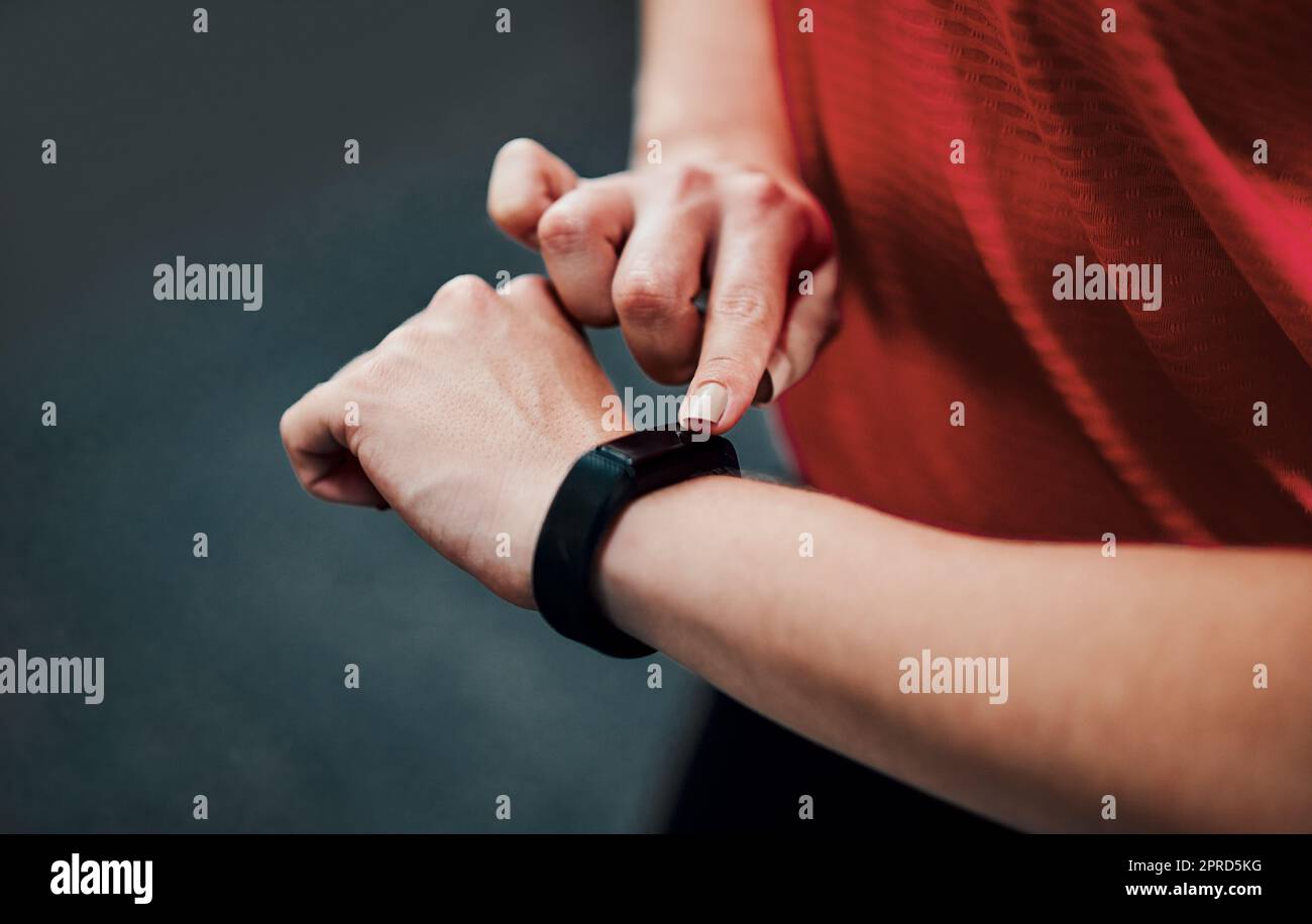 Seguire la sua forma fisica. Una giovane atleta irriconoscibile che controlla il suo smartwatch mentre si allena in palestra. Foto Stock