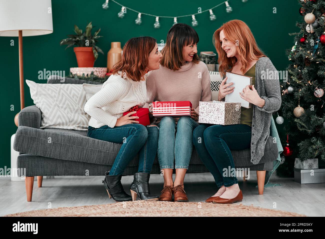 Amici miei, sorelle, tre donne attraenti che scambiano regali di Natale sul divano a casa. Foto Stock