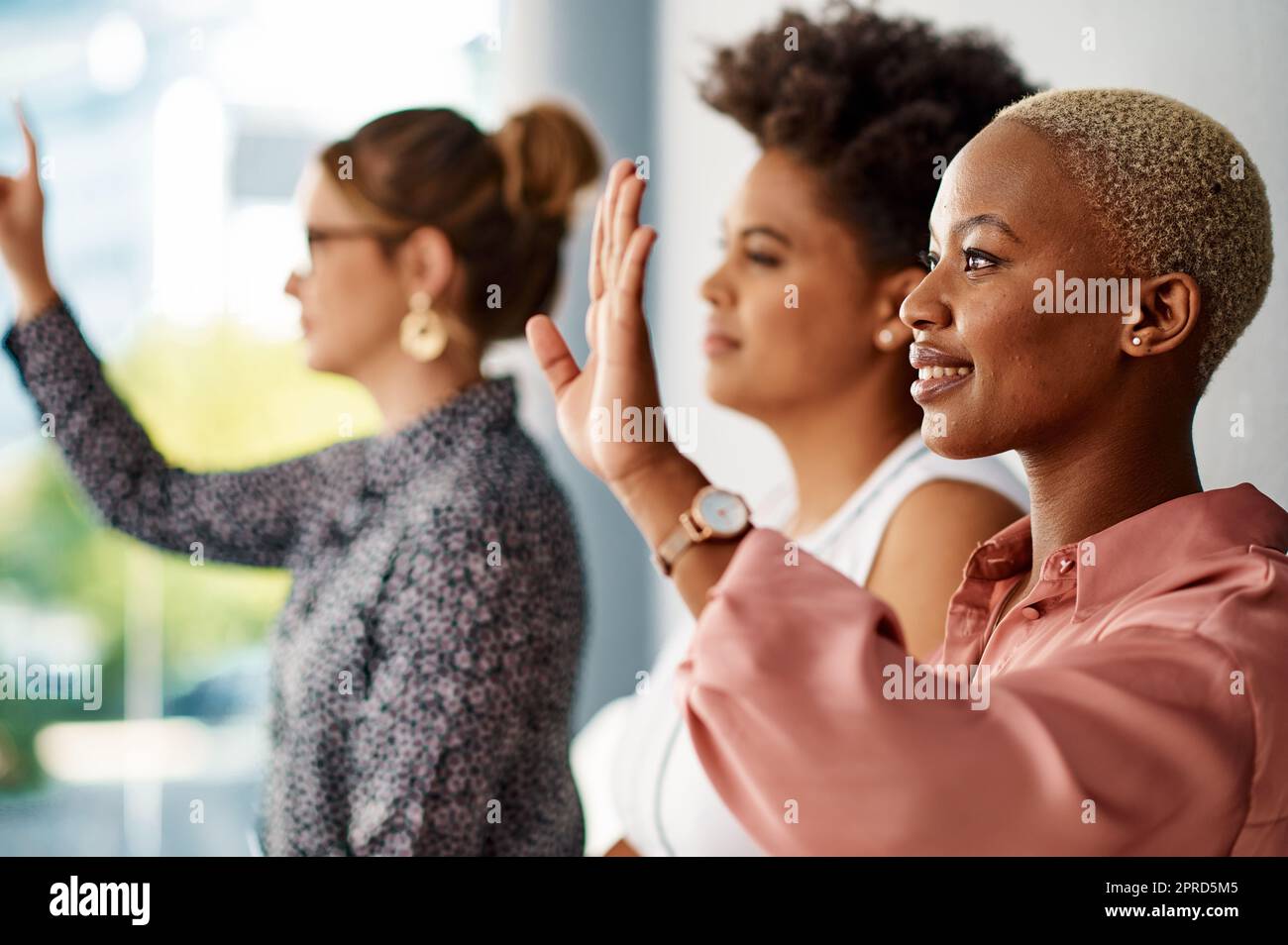 Vorrei fare una domanda: Un gruppo di giovani donne d'affari attraenti che si alzano le mani per porre una domanda durante una conferenza. Foto Stock