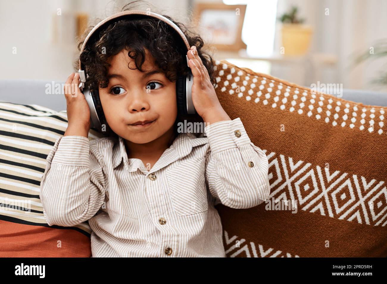 Conosco una buona canzone quando ne sento una. Un ragazzo adorabile che ascolta la musica con le cuffie mentre si siede su un divano a casa. Foto Stock