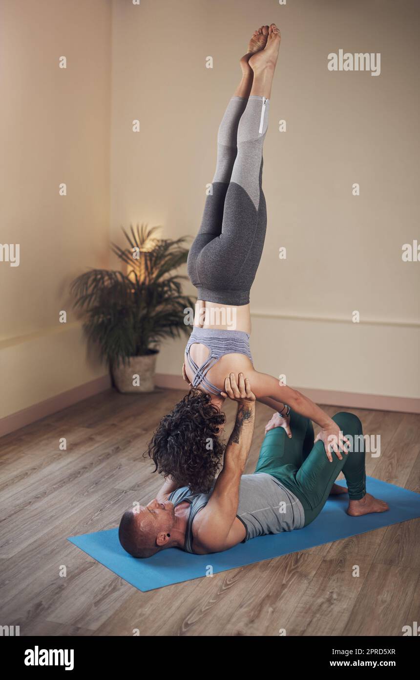 La vita è un atto di equilibrio. Scatto completo di un bel giovane uomo che fa acro yoga con il suo compagno in uno studio di yoga. Foto Stock