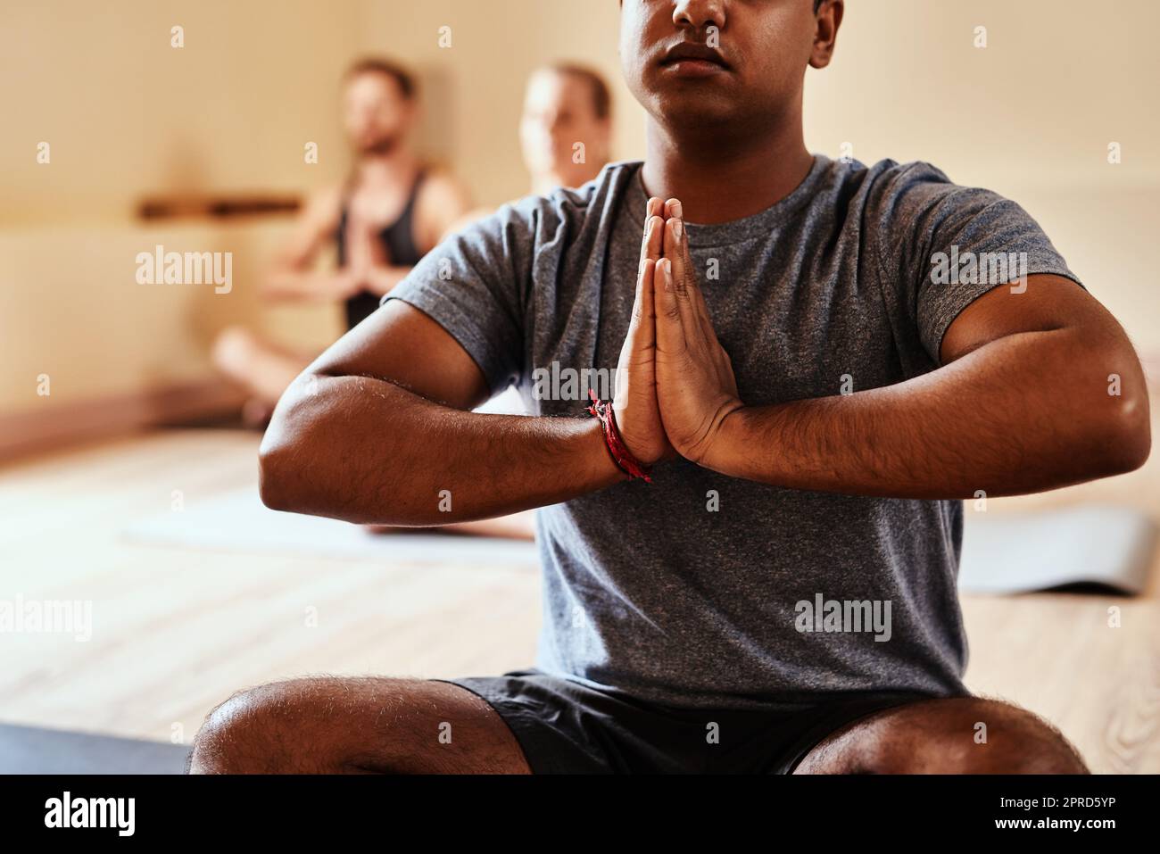 Immerso nella magia dello yoga, un gruppo di giovani uomini e donne che meditano in una lezione di yoga. Foto Stock