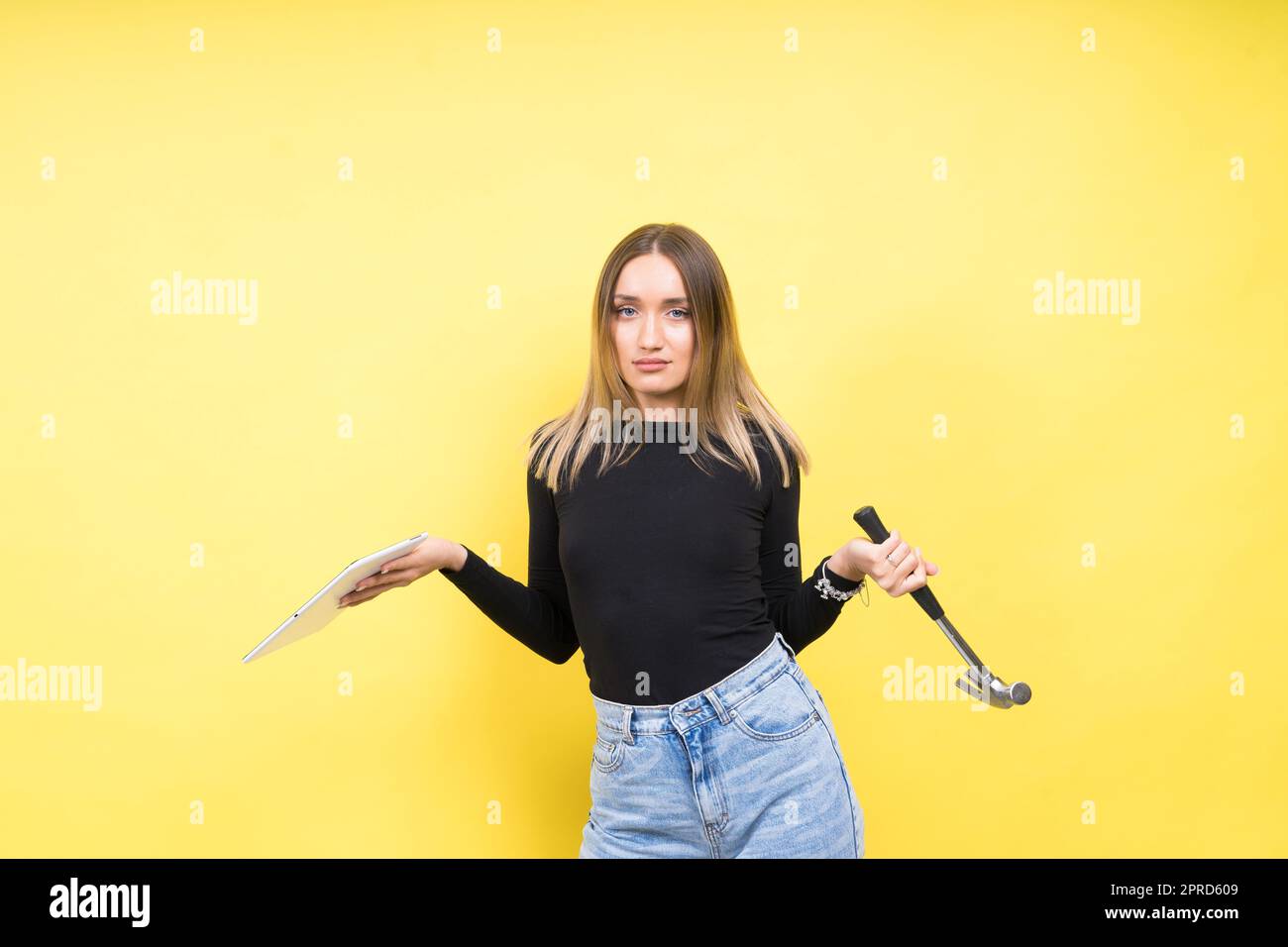 Centro servizi. Riparazione del notebook. Il cacciavite femmina svita i bulloni del computer portatile su sfondo giallo Foto Stock