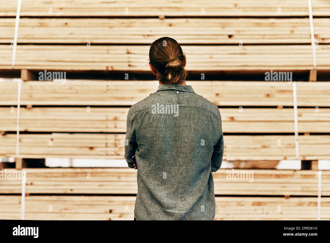 Ci sono un sacco di opzioni tra cui scegliere. Scatto retrostensile di un giovane falegname che guarda un mucchiolo di legno all'interno di un'officina. Foto Stock
