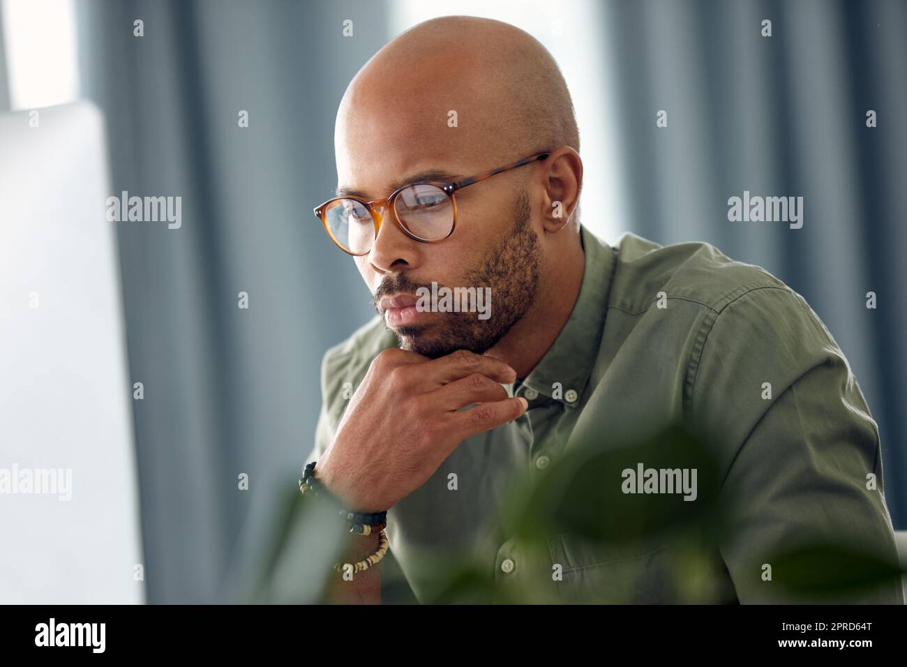 Il mio lavoro richiede molta potenza cerebrale, un giovane uomo d'affari seduto dietro un computer nel suo ufficio. Foto Stock