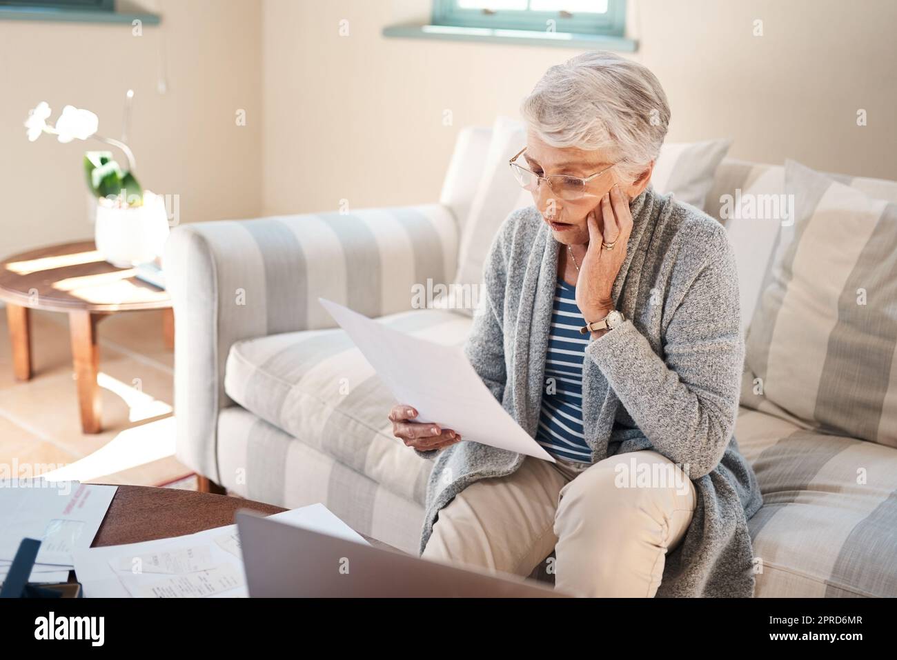 Niente è più distruttivo del debito, una donna anziana che guarda stressata mentre passa attraverso il lavoro di ufficio a casa. Foto Stock