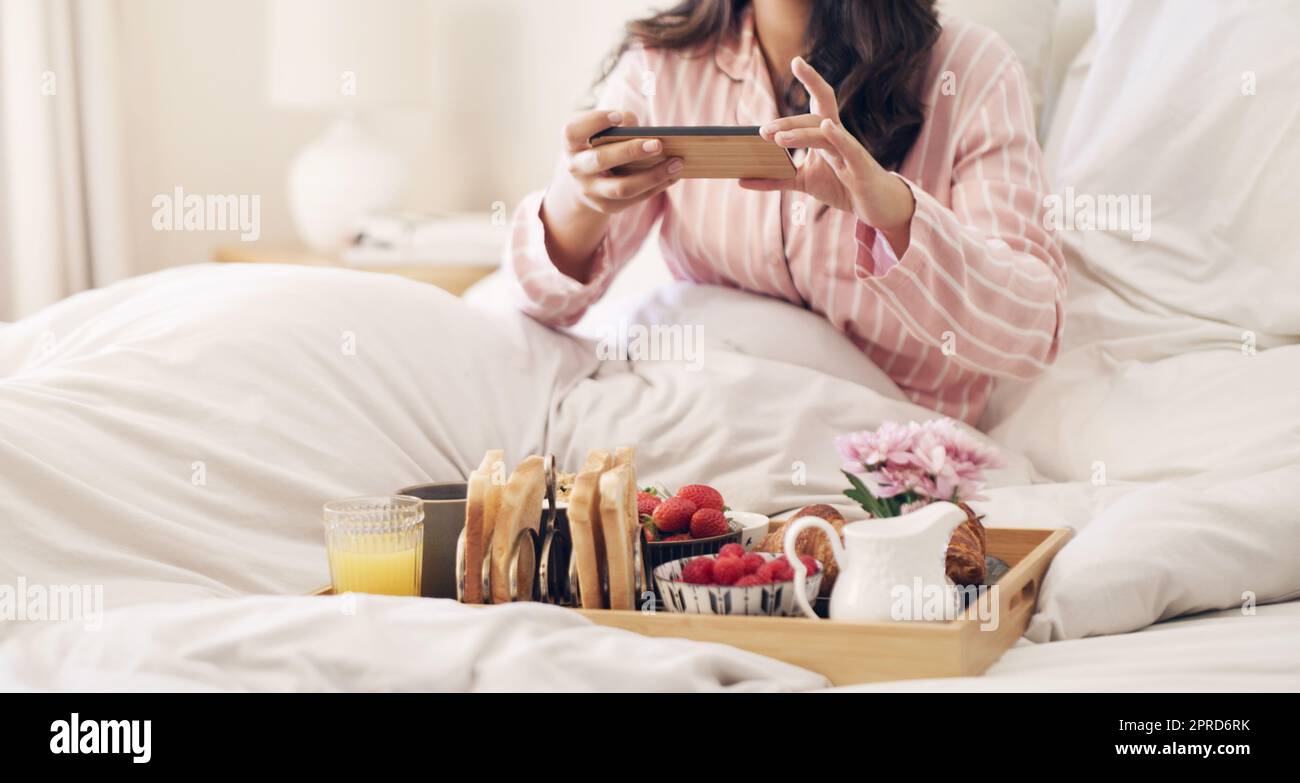 Ecco come inizio la mia mattinata: Una donna che prende una foto della sua colazione a letto a casa. Foto Stock