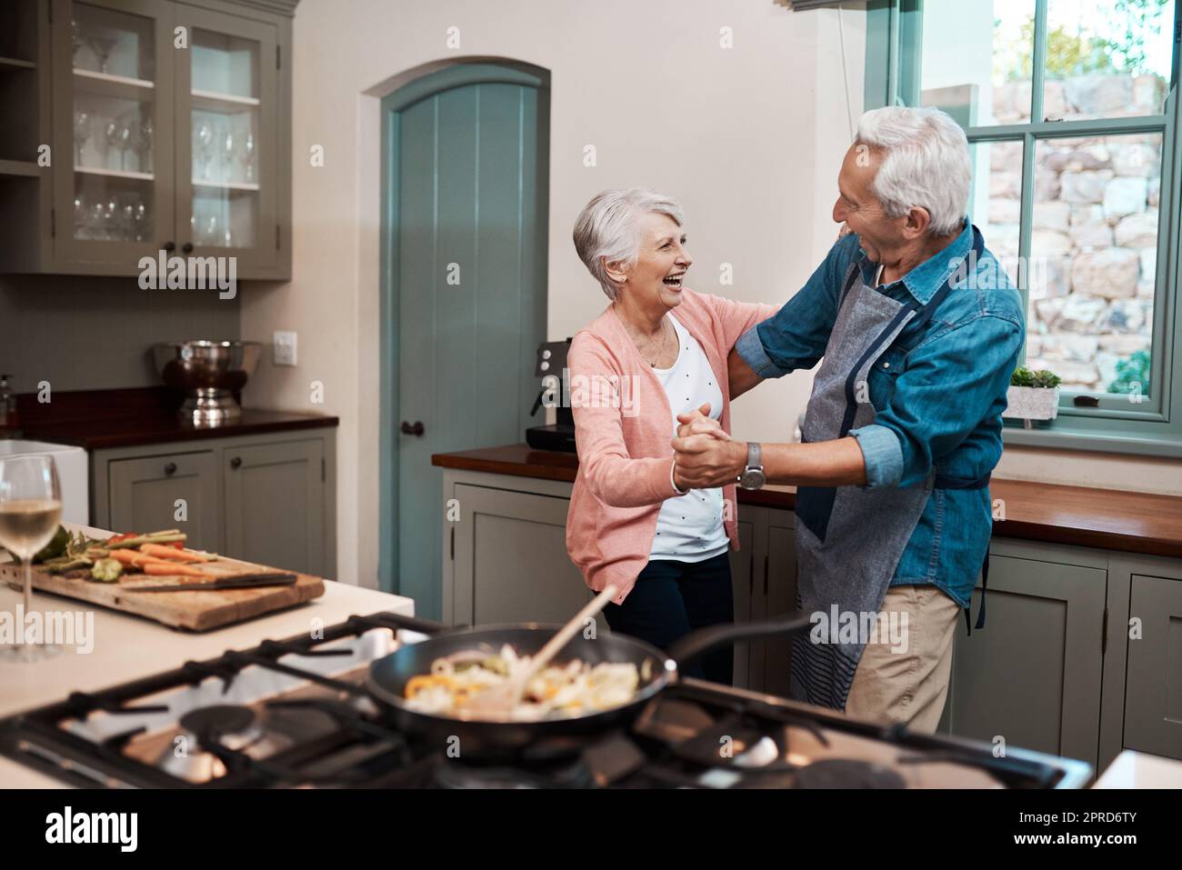 Sappiamo come mantenere forte il nostro amore. Una coppia anziana balla mentre cucinava in cucina a casa. Foto Stock