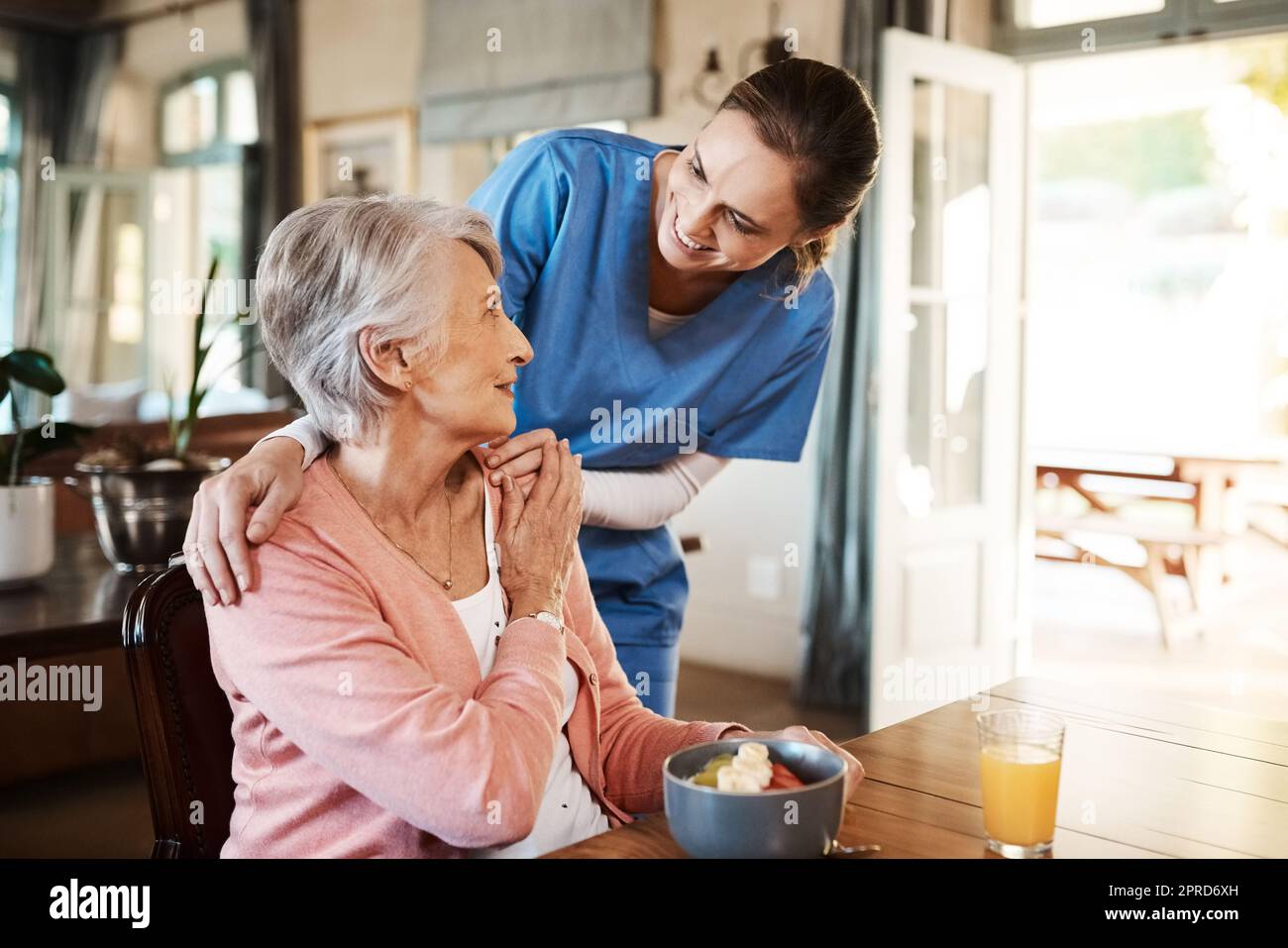 Se vi piace la colazione, una giovane infermiera che fa il check-up su una donna anziana durante la prima colazione in una casa di cura. Foto Stock