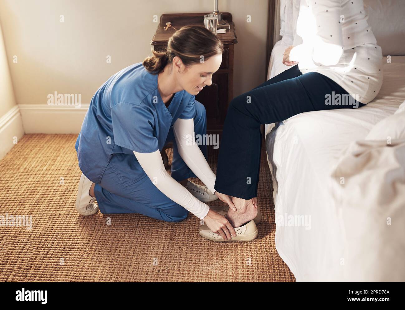 Potremmo tutti usare un piccolo aiuto in questa vita. Una giovane infermiera che aiuta una donna anziana a vestirsi nella sua camera da letto in una casa di cura. Foto Stock