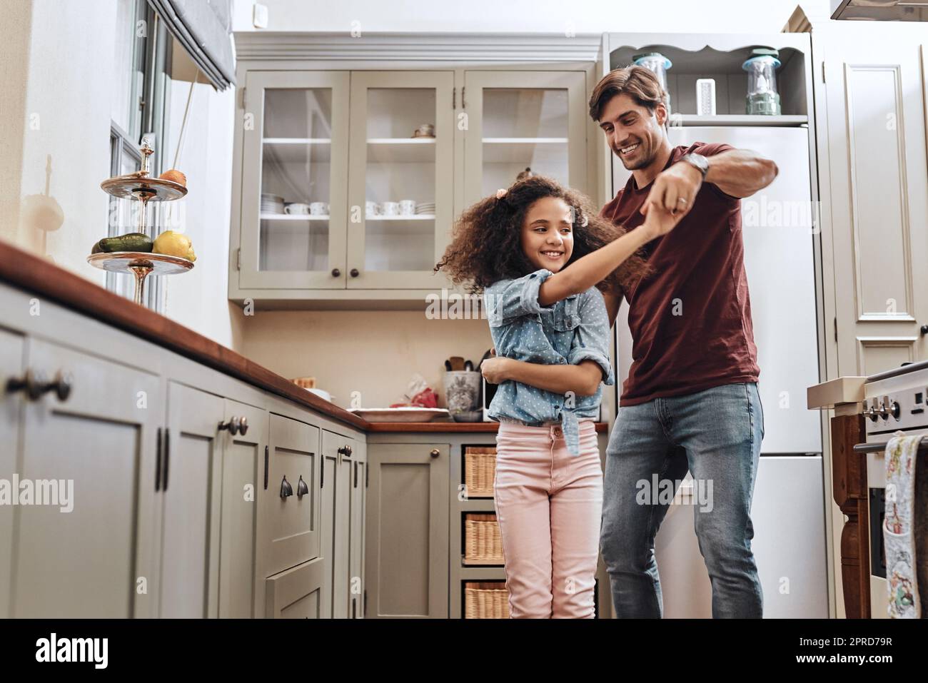 Con le tue grandi mosse, prenderai il seguito di tuo padre: Un uomo e la sua giovane figlia ballano in cucina a casa. Foto Stock