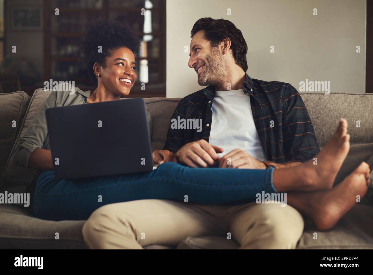 Voglia di marciare attraverso l'inferno per la sua causa celeste. Una giovane coppia felice che usa un laptop mentre si rilassa su un divano nel loro soggiorno a casa. Foto Stock