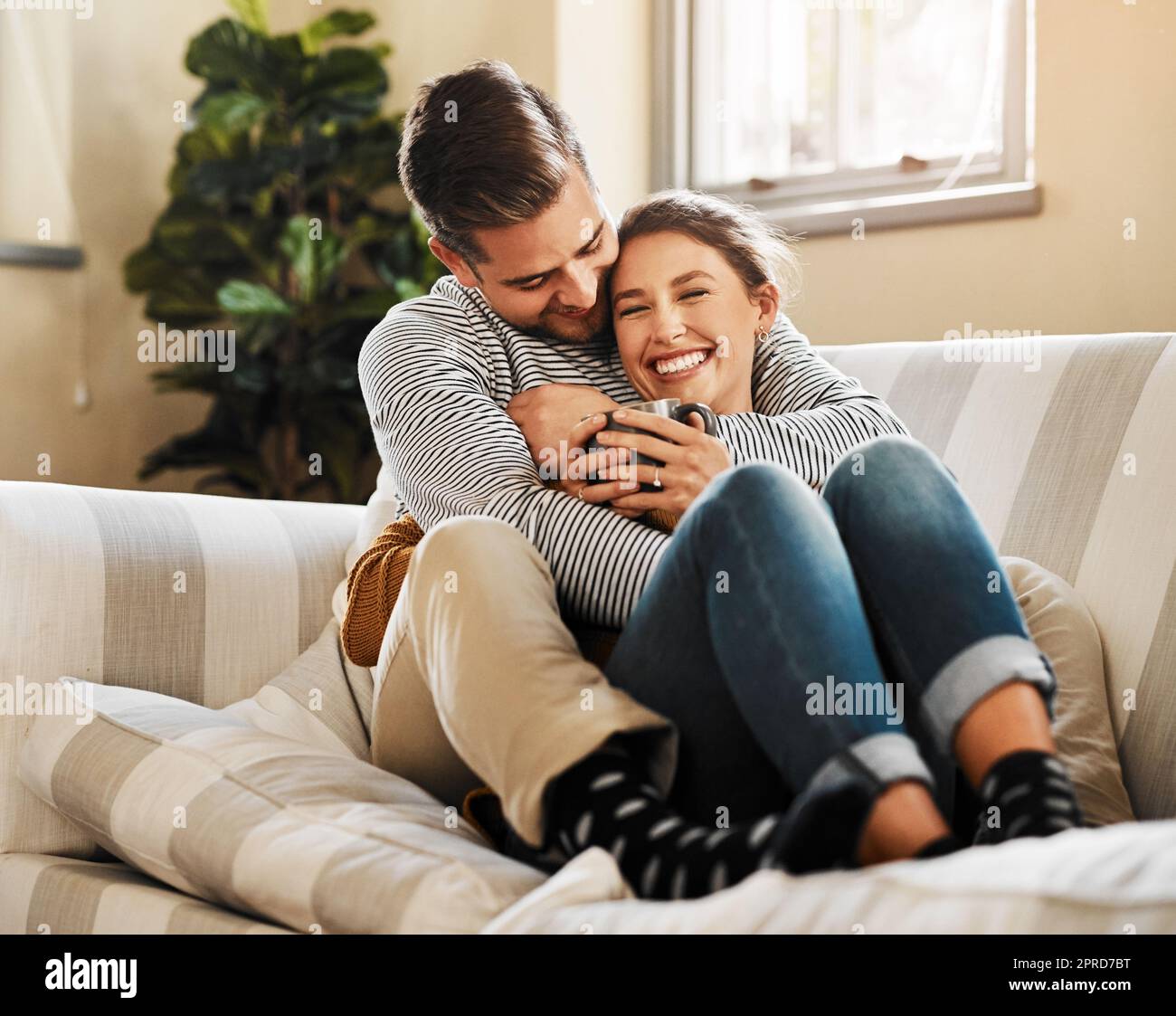 Avete detto che volete coccolare, una giovane coppia che si rilassava sul divano di casa. Foto Stock