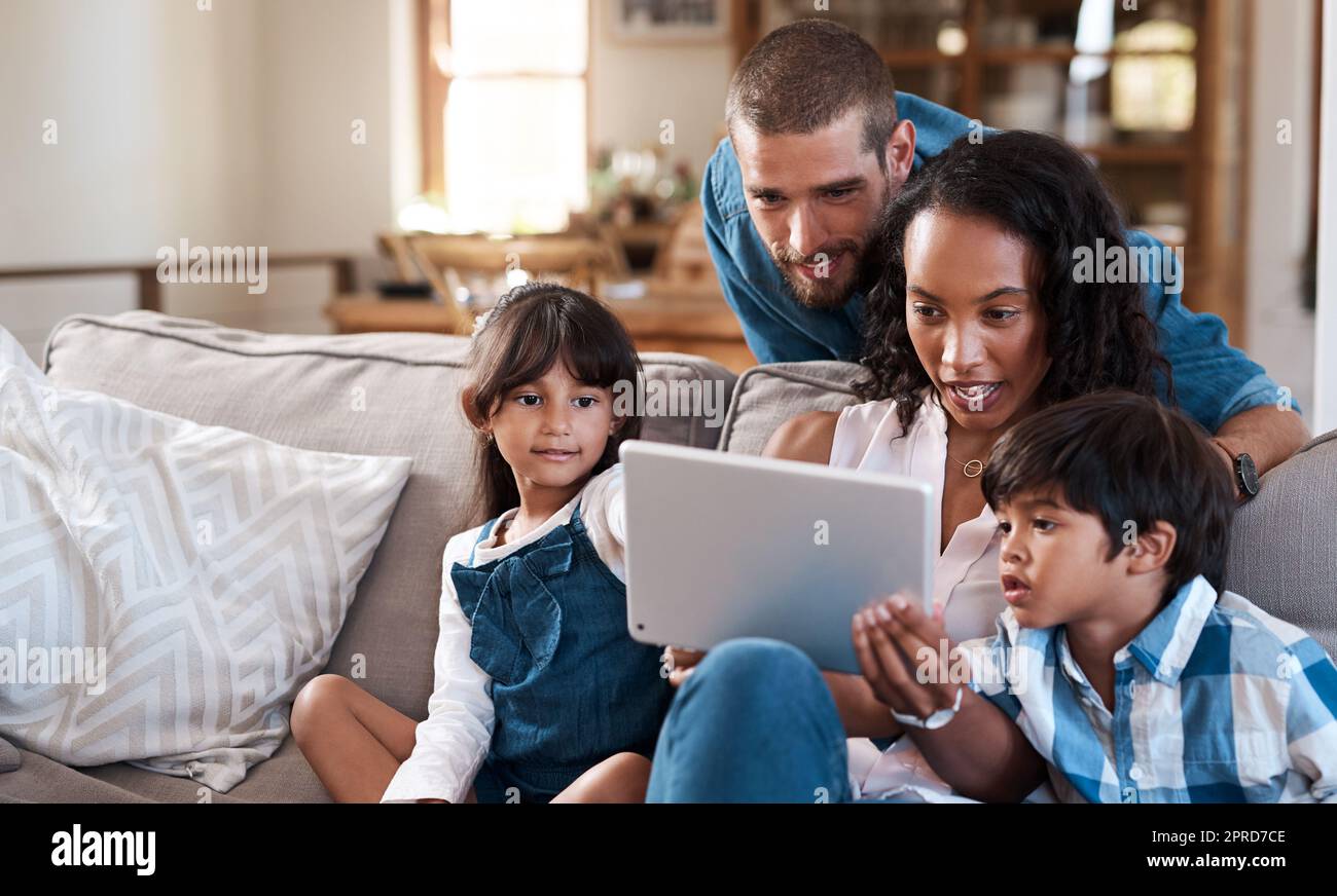 Abbiamo trovato un'app educativa divertente per tutte le età. Una famiglia di quattro persone che guarda qualcosa su un tablet digitale. Foto Stock