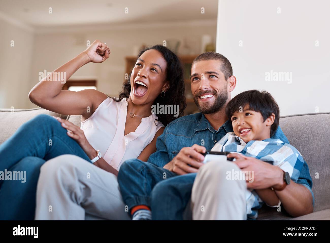 Mamma è il nostro fan più grande: Un uomo che gioca ai videogiochi mentre si rilassa a casa con sua moglie e suo figlio. Foto Stock