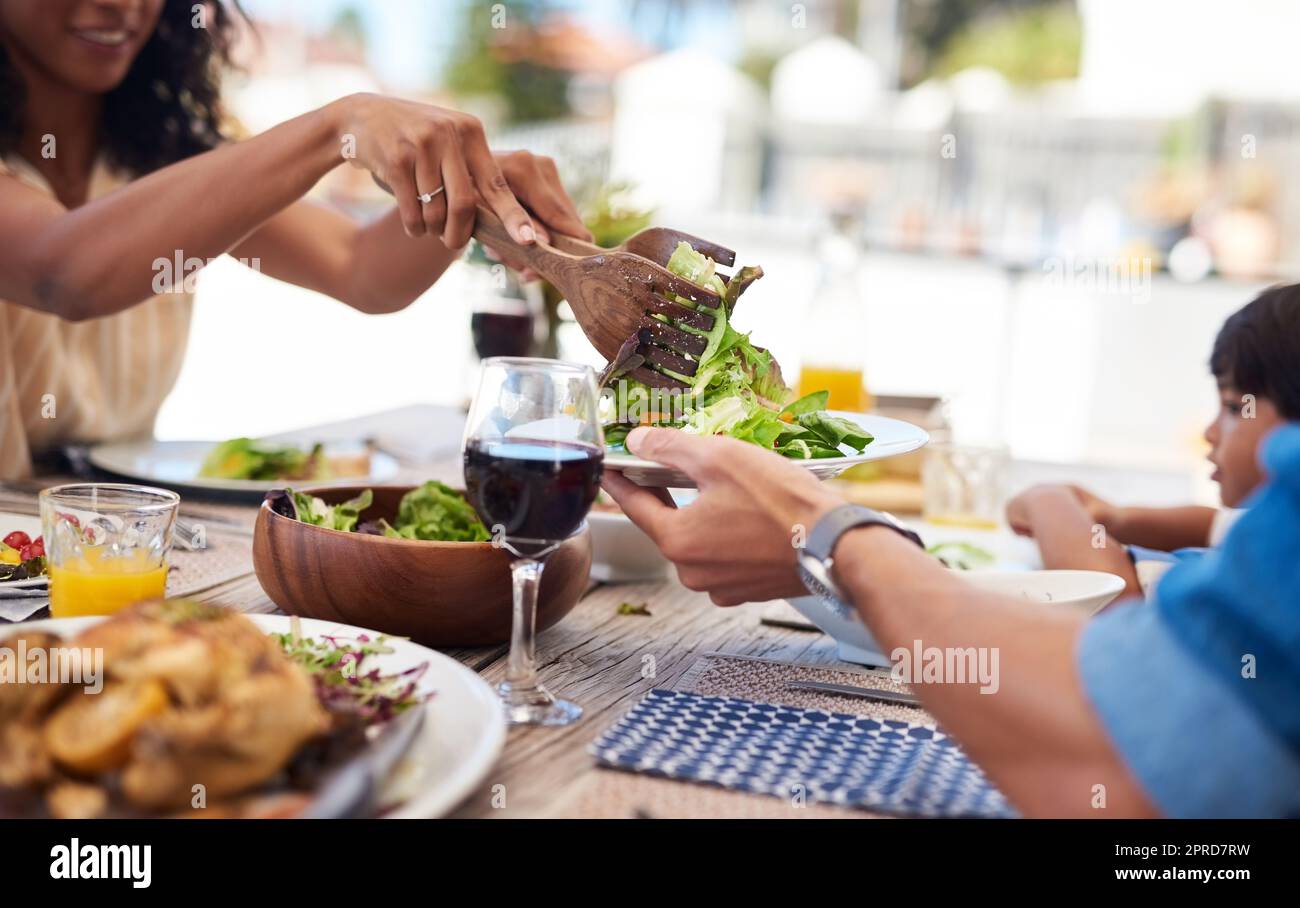 Più verdi per me prego. Una donna irriconoscibile che sta facendo un'insalata sul suo piatto del mariti mentre godendo un pasto con la famiglia all'aperto. Foto Stock