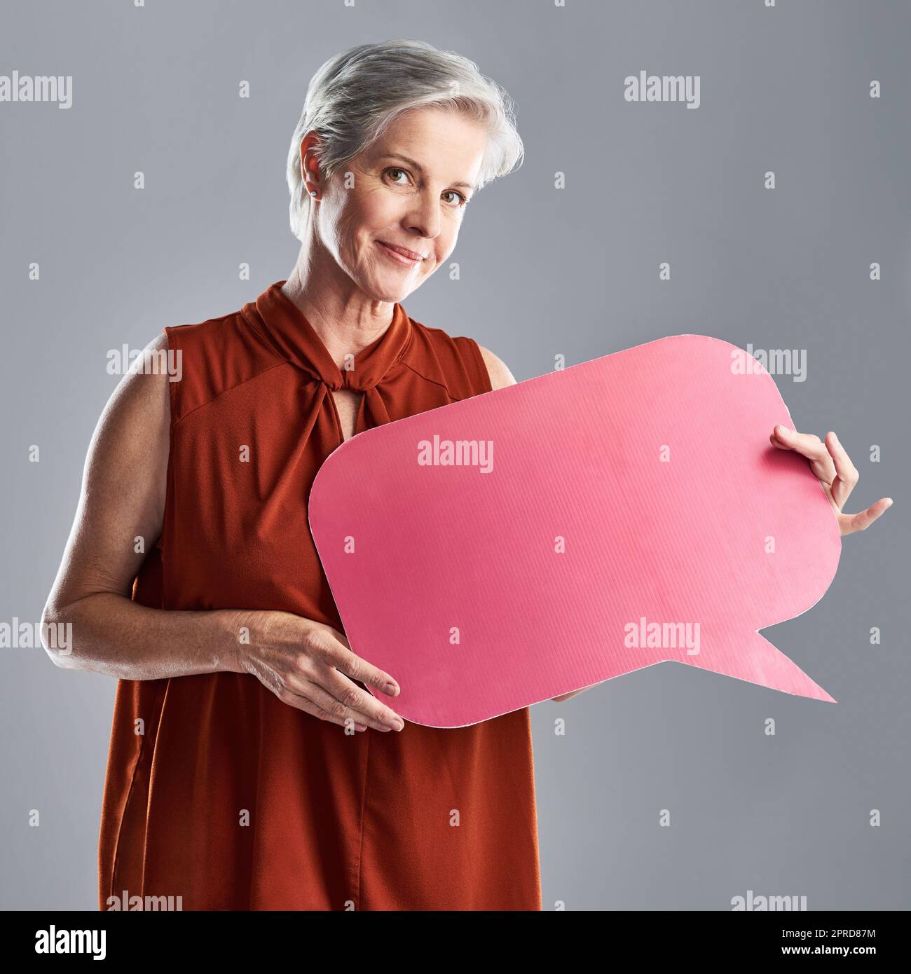 Ive ha ricevuto un messaggio per la generazione più giovane. Ritratto di una donna matura che tiene una bolla di discorso su uno sfondo grigio. Foto Stock