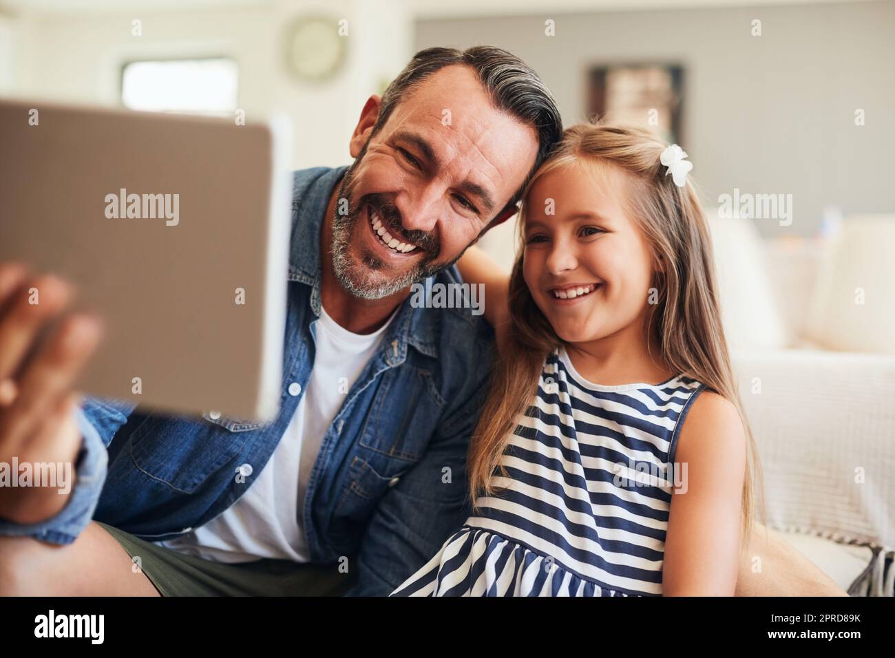 Selfie con la mia piccola signorina Sunshine. Una bambina adorabile che prende selfie con suo padre su un tablet digitale a casa. Foto Stock