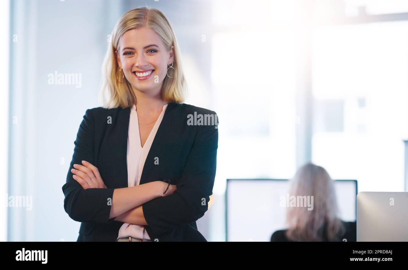È un boss meraviglioso da avere. Ritratto di una giovane donna d'affari fiduciosa in piedi con le braccia ripiegate all'interno dell'ufficio. Foto Stock