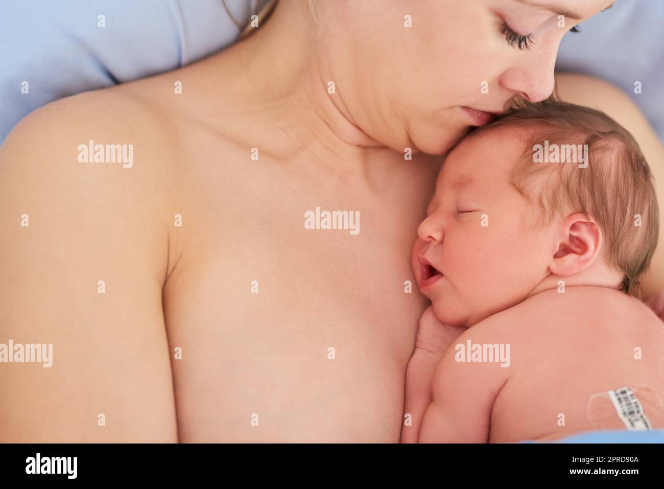 I nostri cuori sono legati insieme per sempre: Una bella giovane madre e la sua neonata bambina che dormono insieme in un letto d'ospedale. Foto Stock