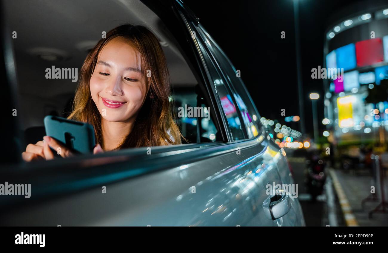 Asian businesswoman pendolando da ufficio in taxi con il telefono cellulare su strada Foto Stock