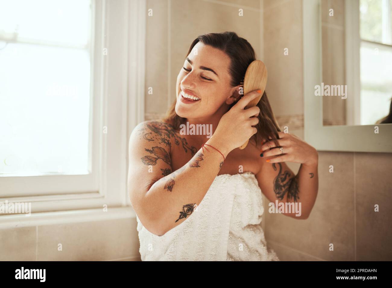 Ama i tuoi capelli e ti ama la schiena. Una giovane donna attraente spazzolando i capelli durante la sua routine di bellezza mattina a casa. Foto Stock