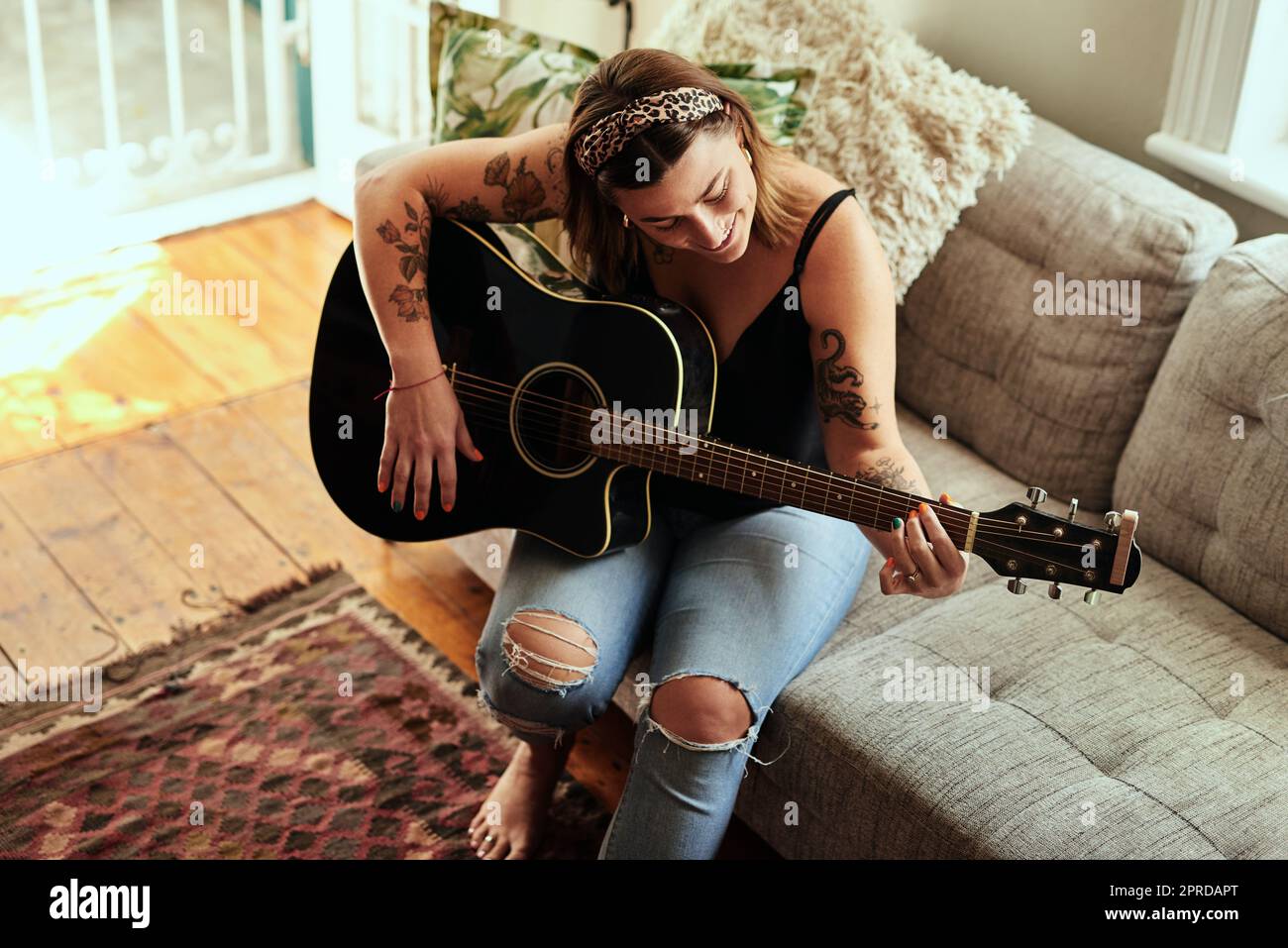 Im More me con una chitarra nelle mie mani. Una giovane donna che suona una chitarra in una giornata rilassante a casa. Foto Stock