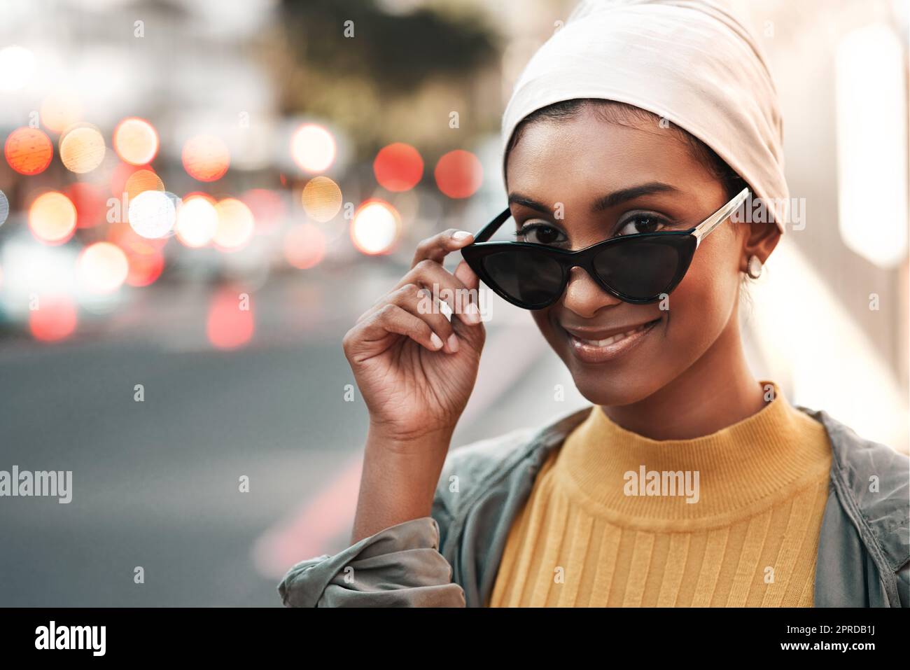 Si tratta di una bella giovane donna che si alza in piedi da sola in città e che guarda alluringly sopra i suoi occhiali da sole. Foto Stock